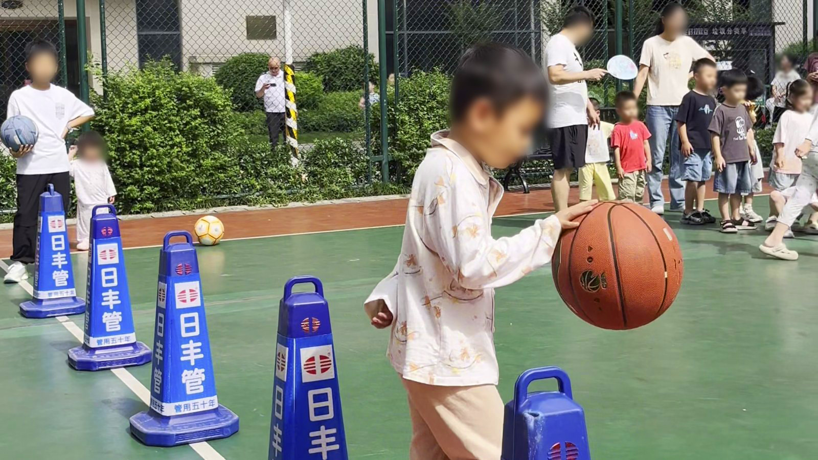 运球绕桩:孩子抱着篮球绕过蓝色障碍