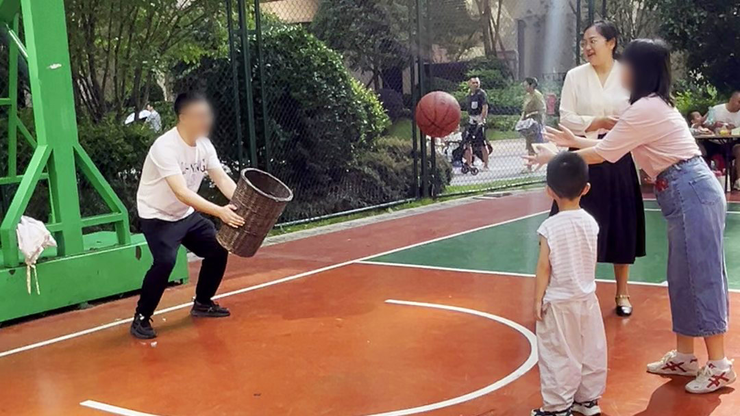 亲子协作:家长举筐接住孩子抛来的篮球